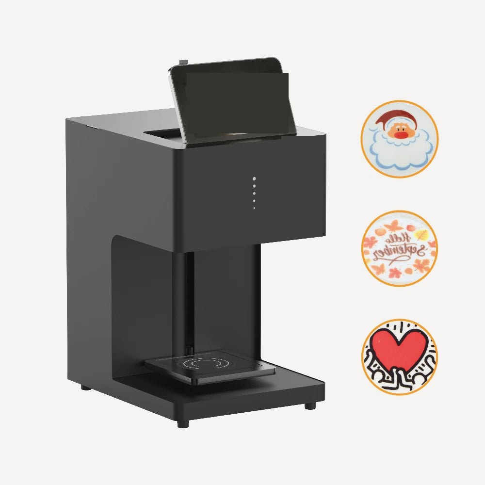 Countertop latte printer with a fold-up screen, beside three example foam prints